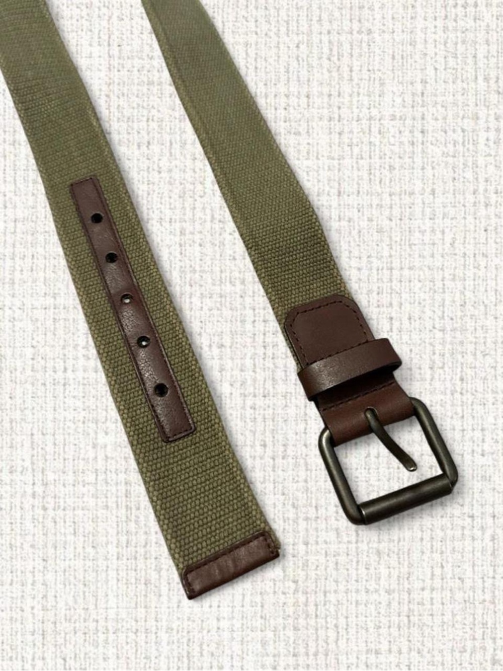 Olive green canvas belt with brown trim and dark metal buckle.